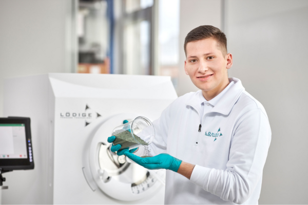 A person in front of a Lödige machine for the pharmaceutical industry.